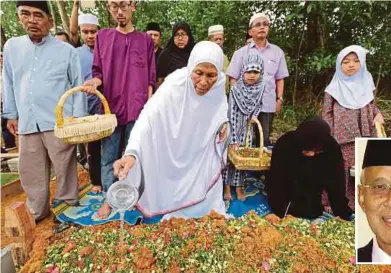  ?? PIC BY MOHD AZREN JAMALUDIN ?? Datin Misbah Sakat pouring rose water over the grave of her husband, Datuk Mohd Ali Hassan (inset) in Johor Baru yesterday.