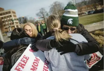  ?? JAKE MAY/THE FLINT JOURNAL ?? Spartan hug: Sue Dodde, a mother from Conklin, Michigan, right, embraces a student with a“free hug from a mom”as the campus reopened for classes Monday at Michigan State University in East Lansing, Mich. One week ago, three students were killed and five others were injured during a mass shooting at the university.