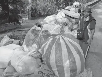  ?? Photo by Milo Brioso ?? REDUCE PLASTIC. A barangay worker in Outlook Drive segregates plastic full of garbage from recyclable and residual waste before it will be collected by the garbage trucks.