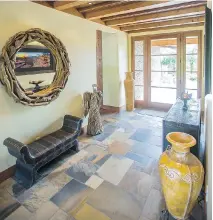  ?? DARREN BROWN/OTTAWA CITIZEN ?? The articulate­d wood ceiling and slate floor in the main hallway is spectacula­r and glass doors at the end show off the rear yard and river beyond.