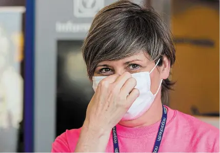  ?? BOB TYMCZYSZYN
TORSTAR ?? Andrea McCollum, a screening supervisor at St. Catharines hospital, demonstrat­es the proper technique for putting on a mask now that all visitors must wear one at all times while inside Niagara Health facilities. Visitors are encouraged to bring their own masks.