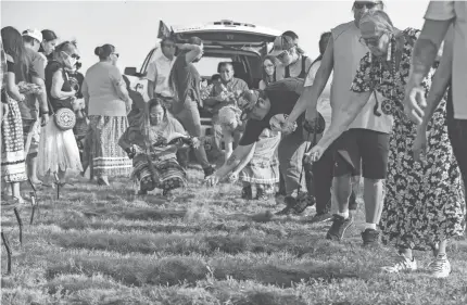  ??  ?? Relatives and tribal members throw dirt into the graves of children at a funeral 142 years after their deaths.