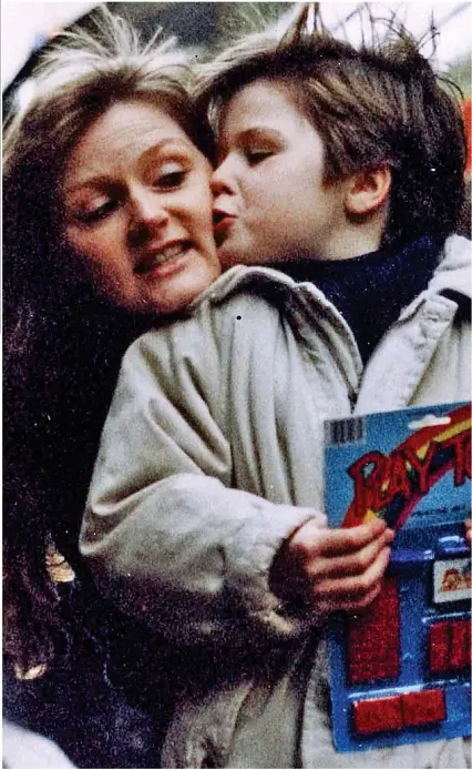  ??  ?? Devoted: Louise Tiffney kisses and cuddles her five-year-old son Sean Flynn during a family day out