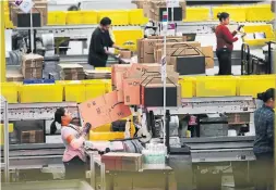  ?? RICHARD LAUTENS TORONTO STAR FILE PHOTO ?? Amazon workers box items for shipping at a fulfilment centre in Brampton in 2017. Last month, Amazon rescinded a bonus program that gave workers a monthly payout based on attendance and productivi­ty.