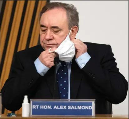  ??  ?? Former first minister Alex Salmond removes his face mask before giving evidence to the Scottish Parliament committee