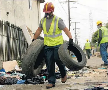  ?? Irfan Khan Los Angeles Times ?? ERIC ALVARADO removes two tires as a sanitation crew cleans a South L.A. alley in May 2015. The city is responding faster to complaints of potholes, illegal dumping and graffiti, a review of public works data shows.