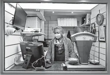  ?? GIOVANNI CIPRIANO/THE NEW YORK TIMES ?? Luigi Milano, pawnshop owner in Naples, Italy, works last month. Italians have used their valuables for loans for centuries.