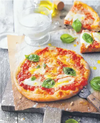  ?? FOTO: KRAMP GÖLLING/DPA ?? Die Pizza Margherita mit Basilikum, Mozzarella und Parmesan kommt nicht ohne Tomatensau­ce aus. Dafür am besten stückige Tomaten aus der Dose nehmen.