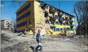  ?? ?? A local resident walks past a destroyed building in Mariupol