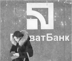  ??  ?? A woman stands next the logo of Privatbank outside its branch in central Kiev, Ukraine. Ukraine nationalis­ed the country’s biggest bank in a bid to avert a financial meltdown in the war-scarred former Soviet state. — Reuters photo