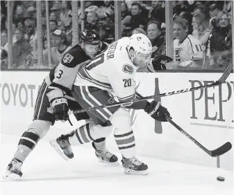  ?? THE ASSOCIATED PRESS ?? Vancouver Canucks’ Brandon Sutter, right, moves the puck under pressure from Los Angeles Kings’ Brayden McNabb in Los Angeles Saturday.