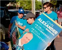  ?? — AFP ?? Supporters of Liberal MP John Alexander pack away banners outside a polling station at the close of voting in the suburban Sydney seat of Bennelong on Saturday.