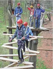  ?? LAKE GENEVA CANOPY TOURS ?? Anders (front) and Maddie Clark cross a moving wooden bridge at Lake Geneva Canopy Tours & Outdoor Adventure Center.