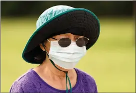  ?? (AP/David J. Phillip) ?? A woman covers up while walking in a park Wednesday in Houston, where the number of people hospitaliz­ed in intensive care continues to rise.