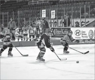  ?? NIKKI SULLIVAN/CAPE BRETON POST ?? Six-year-old Leland MacDonald, in black, breaks away with the puck in hopes of scoring a goal during the Tim Hortons Timbits Jamboree on Sunday at Centre 200.