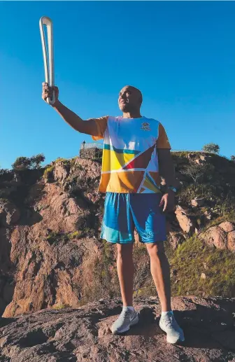  ??  ?? Rugby league legend Gorden Tallis lifts the Queen’s Baton atop Castle Hill in Townsville yesterday as it continues on its journey to the Gold Coast.