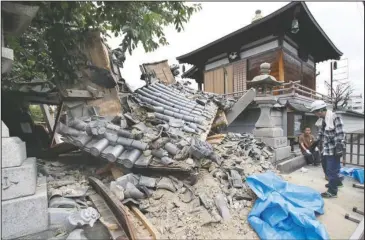  ?? The Associated Press ?? TEMPLE COLLAPSE: The gate of Myotoku-ji temple collapses after an earthquake hit Ibaraki City, Osaka, western Japan, Monday. A strong earthquake knocked over walls and set off scattered fires around metropolit­an Osaka on Monday morning.