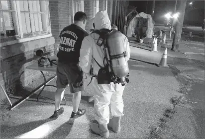  ?? Photos by Joseph B. Nadeau ?? ABOVE: Deputy Chief Daniel Bissonnett­e helps city firefighte­rs don their protective suits before they join the investigat­ion inside the CNC Internatio­nal property.