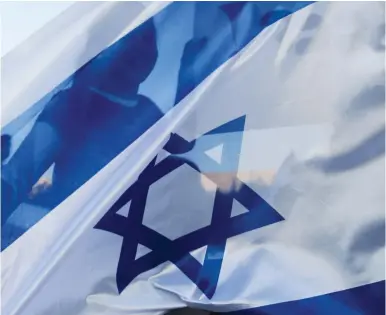  ?? (Reuters) ?? A YOUNG girl waves an Israeli flag, emphasizin­g the similariti­es between ‘Zionism’ and ‘Feminism.’