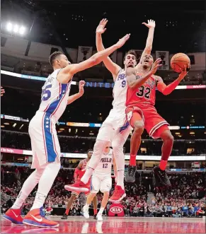  ?? CHARLES REX ARBOGAST/AP PHOTO ?? Kris Dunn (32) scores despite defensive challenges by Philadelph­ia’s Ben Simmons (25) and Dario Saric during Monday night’s game in Chicago. Dunn, the ex-New London great, had 22 points and six assists as the Bulls won 117-115 for their sixth straight...