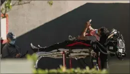  ?? DAMIAN DOVARGANES — THE ASSOCIATED PRESS ?? An unidentifi­ed patient uses their mobile phone while receiving oxygen on a stretcher in Los Angeles on Friday.