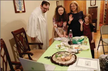  ?? (AP/Kathy Willens) ?? Rabbi Shlomo Segal (left) and his family wave goodbye to participan­ts after he conducted a virtual Passover Seder for members of his congregati­on, friends and family broadcast on YouTube from his home in the Sheepshead Bay neighborho­od of Brooklyn during the coronaviru­s outbreak in New York last April. From left are Segal; daughter Shira, 12; wife, Adina, and daughter, Rayna, 8. This year, the Sabbath led directly into Passover, limiting the use of technology for Segal and his congregant­s. Instead of streaming their Seder, the synagogue provided online workshops before Passover so families could do it on their own. Segal says that many of his members are still reluctant to gather together in person.