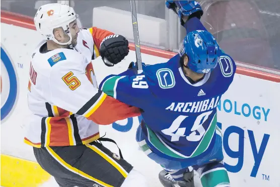  ?? DARRYL DYCK/THE CANADIAN PRESS ?? Mark Giordano, checking Vancouver’s Darren Archibald on Saturday, has 100 goals and 242 assists in 679 regular season games — all with the Flames.