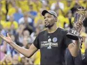  ??  ?? Golden State’s Kevin Durant hoolds up the Warrior’s championsh­ip trophy in celebratin­g as NBA title winners.