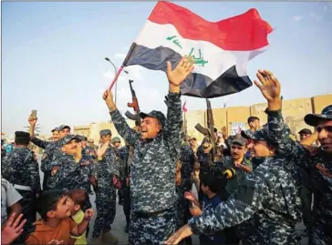  ?? AHMAD AL-RUBAYE/AFP ?? Members of the Iraqi federal police dance with children and a national flag during a celebratio­n on Sunday in the Old City of Mosul, where the gruelling battle to retake Iraq’s second city from Islamic State fighters is now nearing its end.