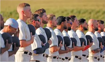  ?? MICHAEL REAVES/GETTY IMAGES ?? With the sun against their backs, Cubs players stand for the national anthem.