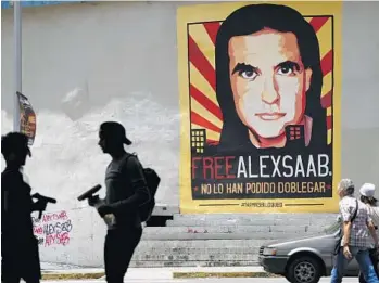  ?? ARIANA CUBILLOS/AP ?? Pedestrian­s walk near a poster of Alex Saab that reads in Spanish “Alex Saab Free. They haven’t been able to bend him,” in Caracas, Venezuela, on Sept. 9, 2021. Newly unsealed court records show the Colombian businessma­n linked to Venezuelan President Nicolas Maduro was secretly signed up by the U.S. Drug Enforcemen­t Administra­tion as a cooperatin­g source in 2018 and gave agents informatio­n about bribes he paid to Venezuelan officials.