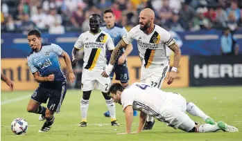  ?? GARY A. VASQUEZ/USA TODAY ?? Whitecaps forward Nicolas Mezquida moves the ball ahead of Galaxy defender Jelle Van Damme, right, and defender Dave Romney, on ground, at the StubHub Center in L.A. on Wednesday.