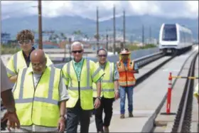  ?? CATHY BUSSEWITZ — ASSOCIATED PRESS ?? In this May 30 photo, rail executive Krishniah Murthy, front left, and Honolulu Mayor Kirk Caldwell, center, walk along the rail line to a press conference after a train completed a test-run on the tracks in Waipahu, Hawaii. Honolulu’s planned $9.5...