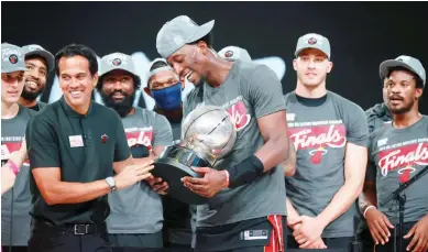  ?? (AFP) ?? Bam Adebayo of the Miami Heat, with Fil-Am head coach Erik Spoelstra, holds up the Eastern Conference Championsh­ip Trophy after winning Game 6 over the Boston Celtics 125-113 yesterday and advancing to the NBA Finals against the Los Angeles Lakers at AdventHeal­th Arena in Orlando, Florida.