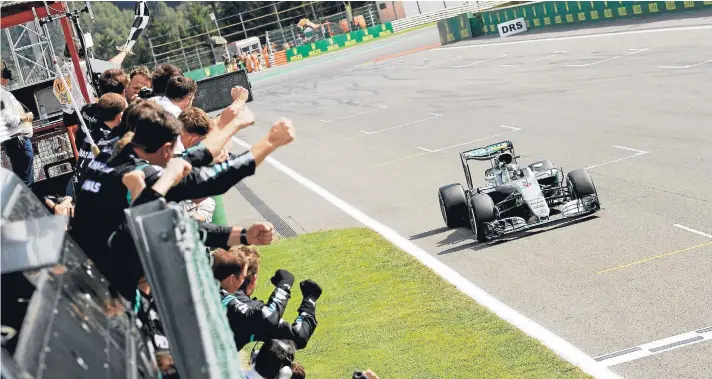  ??  ?? Nico Rosberg cruza la meta en Bélgica y los miembros del equipo Mercedes lo reciben festejando.