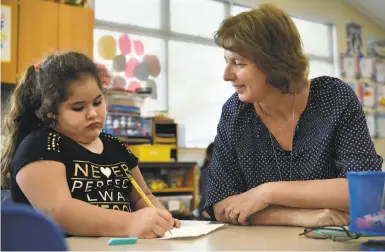  ??  ?? Top: Richard Crane Elementary School Principal Teresa Ruffoni checks work by fourth-grader Andres Garcia. Center: Ruffoni walks the school grounds. Above: Ruffoni talks with second-grader Cristina Alcala.