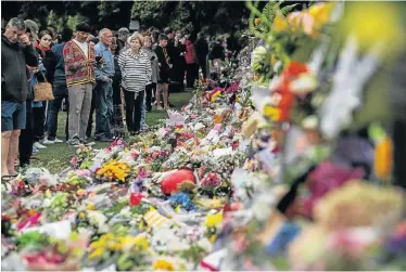  ?? Picture: CARL COURT/GETTY IMAGES ?? NATION MOURNS: Residents look at the flowers and tributes at the wall of the Botanic Gardens on Sunday in Christchur­ch following the shooting, above, while women comfort each other, below