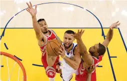  ?? (Reuters) ?? GOLDEN STATE WARRIORS guard Stephen Curry (center) splits a pair of Houston Rockets defenders on his way for two of his game-high 35 points in Sunday night’s 126-85 Warriors’ home victory over the Rockets to take a 2-1 lead in the Western Conference...