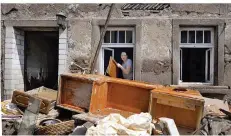  ?? FOTO: HARALD TITTEL/DPA ?? In Fischbach im Kreis Birkenfeld wirft eine Frau nach dem Unwetter vom Sonntag ihr kaputtes Mobiliar aus dem Fenster.