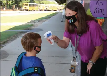  ?? (AP/Newton County Schools/Janine Vincent) ?? Teaching assistant Crystal May takes the temperatur­e of kindergart­en student Lewis Henry Thompson, 5, on Monday at Newton County Elementary School in Decatur, Miss.