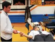  ??  ?? Devon Prep Senior Luke Farnsworth of Royersford (left) uses card tricks to entertain his classmate John DePalo of Downingtow­n as he gives blood during the school’s annual Red Cross Blood Drive.