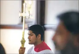  ??  ?? ALTAR SERVER David Onofre, 15, carries a procession­al cross during the service at the Church of the Epiphany, which has a significan­t Latino population.