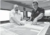  ?? POOL PHOTO BY GRAHAM TIDY ?? Search officials Mike Barton, left, and Alan Lloyd of the Australian Maritime Safety Authority in Canberra look over maps of the Indian Ocean on Sunday.