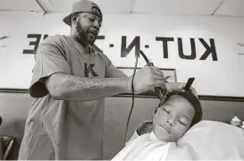  ?? Steve Gonzales / Houston Chronicle ?? Seven-year-old Earrius Napper receives a free haircut by Kut N Zone barber Mokeba Derry during an annual back-to-school event near NRG Stadium.