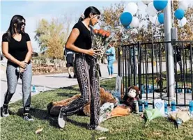  ?? MARIO TAMA/GETTY ?? A student brings flowers Friday to a makeshift memorial in Central Park to victims of the shooting at nearby Saugus High School in Santa Clarita, California. Two students died.