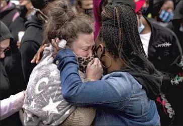  ?? Stephen Maturen Getty Images ?? KATIE WRIGHT, left, mother of Daunte Wright, is embraced during a vigil for her son on Monday in Brooklyn Center, Minn. The police chief there said the shooting of the 20-year-old was an “accidental discharge.”