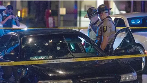  ?? TYLER LARIVIERE/SUN-TIMES ?? Illinois state troopers and Chicago police investigat­e a bullet-riddled vehicle parked in front of Rush Hospital on Aug. 13. The vehicle was involved in a shooting on the Eisenhower Expressway near Ashland Avenue in which three people were wounded, one fatally.