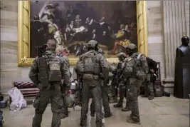  ?? J. Scott Applewhite The Associated Press ?? After rioters stormed the U.S. Capitol, a tactical team from the Bureau of Alcohol, Tobacco, Firearms and Explosives gathers in the Rotunda to provide security for the continuati­on of the joint session of the House and Senate to count the Electoral College votes.