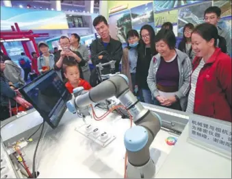  ?? CHEN XIAOGEN / FOR CHINA DAILY ?? Visitors watch an intelligen­t mechanical device equipped with 5G technology in operation during an exhibition in Beijing.