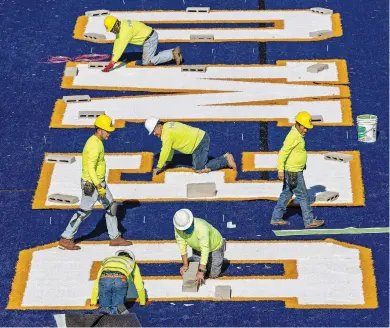  ?? ?? ABOVE: Contractor­s with Hellas Constructi­on of Austin, Texas, work Tuesday to put some finishing touches on new turf at Santa Fe High’s Ivan Head Stadium. Work is scheduled to be finished next week.